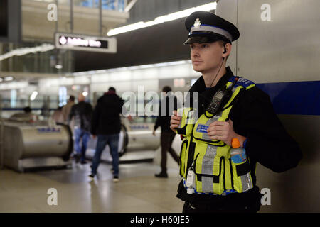 Un agent de police se tient dans le hall d'entrée de la station de métro Canary Wharf. Banque D'Images