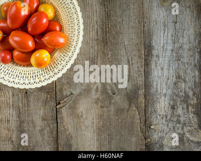 Vue aérienne de tomates raisin frais dans un bol blanc placé sur les planches de bois rustique Banque D'Images