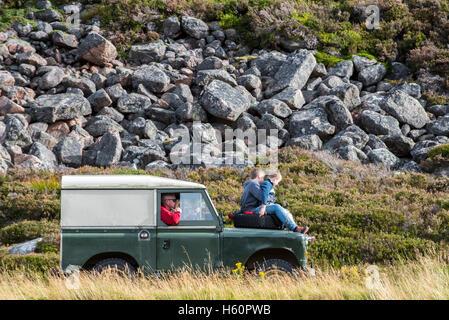 Deux enfants sur le capot de la vieille 4x4 Land Rover jeep conduite dans les montagnes Banque D'Images