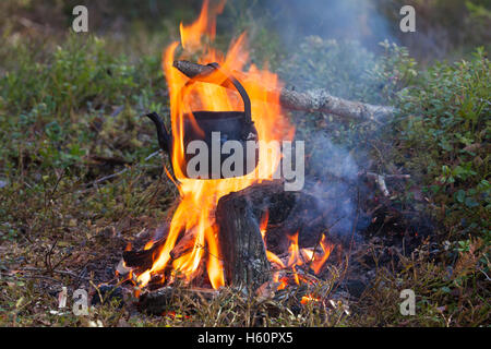 Étain noirci électrique à partir de la suie de l'eau bouillante sur feu de camp pendant la randonnée en forêt Banque D'Images