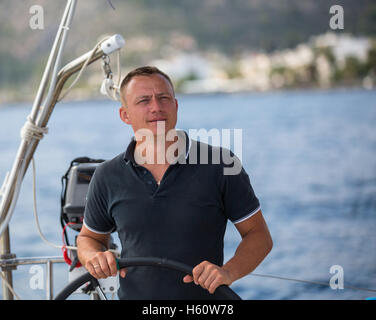 Jeune homme à la barre d'un yacht à voile. Banque D'Images