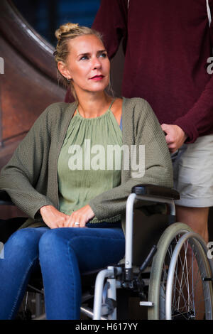 Woman in wheelchair devant l'entrée avec un ami Banque D'Images