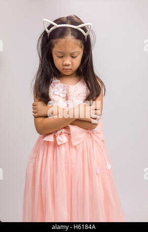 Kid avec serre-tête oreilles de chat en robe rose, isolé sur fond blanc. Banque D'Images