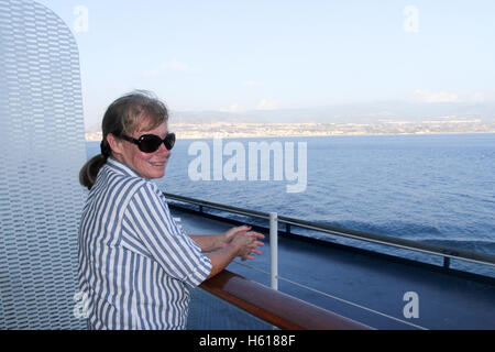 A senior woman bénéficie d'avis à partir d'un bateau croisière à travers le détroit de Messine, Italie Banque D'Images