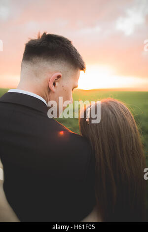 Marié est tenue et d'embrasser son épouse sur l'arrière-plan le coucher du soleil Banque D'Images