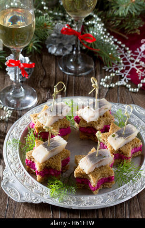 Maison de vacances : apéritif canapés sous la forme d'une étoile à hareng mariné, betterave et trempette aneth sur une table de Noël. Banque D'Images