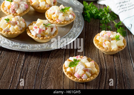 Maison de vacances apéritif : tartelettes au crabe avec des bâtons, le fromage et l'ananas sur une table en bois. Banque D'Images