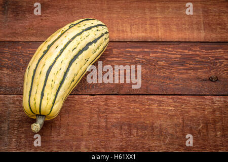 La courge delicata rustique en bois peint rouge contre table grange avec une copy space Banque D'Images