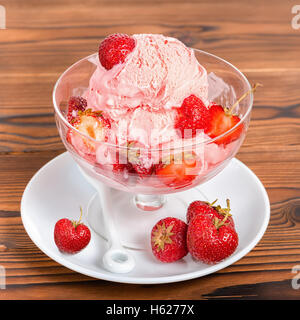 Délicieux dessert fraise vanille rose boules de glace avec des fraises fraîches dans un bol sur fond de bois, Close up Banque D'Images