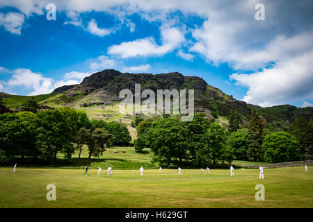 Un jeu de cricket village ci-dessous les collines de Coniston dans le Lake District Banque D'Images