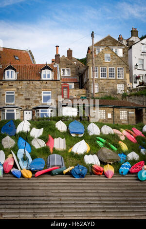 Kayaks et bateaux alignés devant les rues en pente de Runswick Bay. Banque D'Images