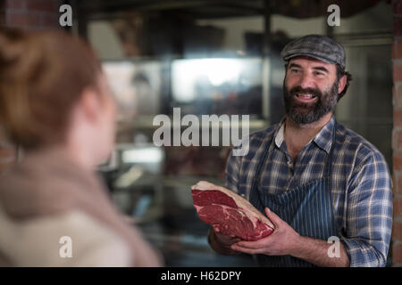 Butcher montrant la viande pour femme en boucherie Banque D'Images