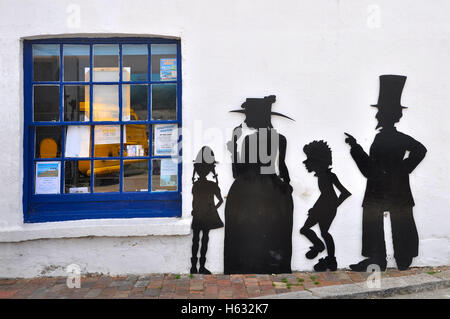 Découpe de l'oeuvre d'une silhouette à côté de la famille fenêtre café à Swanage, Dorset. Banque D'Images