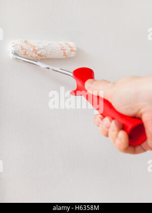 Rénovation d'appartement - peintre peint wall with paint roller Banque D'Images