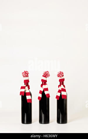 Joyeux Noël et bonne année. Trois bouteilles de vin dans les bouchons et les écharpes à rayures rouges et blanches sur un white background Banque D'Images