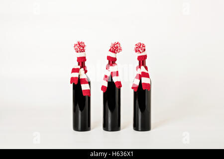 Joyeux Noël et bonne année. Trois bouteilles de vin dans les bouchons et les écharpes à rayures rouges et blanches sur un white background Banque D'Images