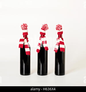 Joyeux Noël et bonne année. Trois bouteilles de vin dans les bouchons et les écharpes à rayures rouges et blanches sur un white background Banque D'Images