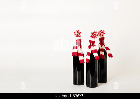 Joyeux Noël et bonne année. Trois bouteilles de vin dans les bouchons et les écharpes à rayures rouges et blanches sur un white background Banque D'Images