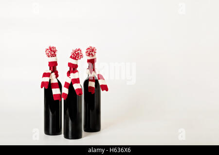 Joyeux Noël et bonne année. Trois bouteilles de vin dans les bouchons et les écharpes à rayures rouges et blanches sur un white background Banque D'Images