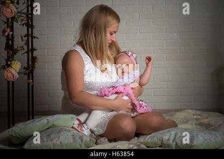 Maman met au lit une petite fille Banque D'Images