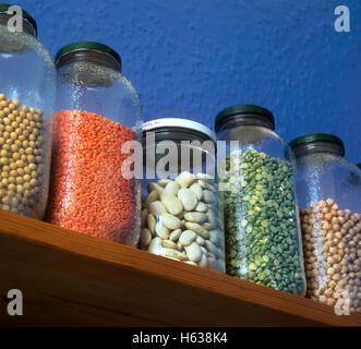 Pulsations dans les bocaux de stockage sur une étagère de cuisine. De gauche à droite : Fèves de soja, de lentilles rouges, haricots beurre, pois cassés verts, pois chiches. Banque D'Images