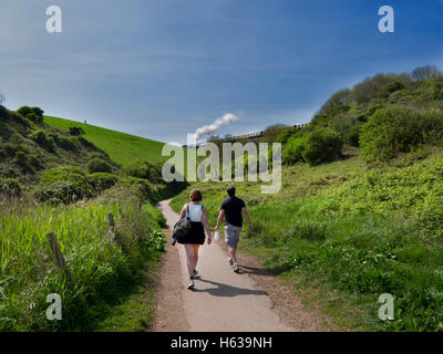 Jeune couple en train de marcher dans la campagne profitez d'une belle vue sur le chemin de fer à vapeur près de broadsands, Devon. Banque D'Images