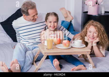 Laughing little girl holding cupcake berry avec ses grands-parents Banque D'Images