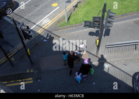 Famille d'immigrants sur la chaussée près de feux de circulation, Glasgow, Ecosse Banque D'Images