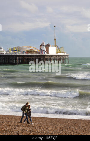 Un couple en train de marcher sur la plage de Brighton, Brighton Pier en arrière-plan, Brighton, East Sussex England UK Banque D'Images