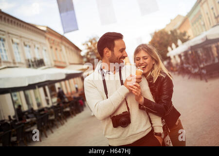 Tourist couple partageant la crème glacée à l'extérieur et smiling Banque D'Images