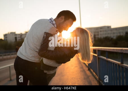 Couple kissing dating sur bridge au coucher du soleil Banque D'Images