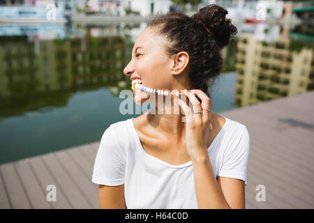 Happy young woman biting dans candy necklace Banque D'Images