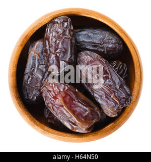Medjool dates séchées du Maroc dans un bol en bois sur fond blanc, appelé aussi Mejhool. Grand, doux et de fruits succulents. Banque D'Images