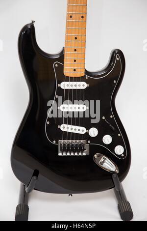 Une copie fender stratocaster noire guitare électrique corps, avec un manche en érable, sur un stand Banque D'Images