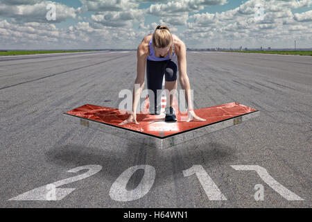 Coureuse à genoux en position de démarrage sur une plate-forme rouge flèche flottante, qui est placé au-dessus de la surface de la piste d'un aéroport. Banque D'Images