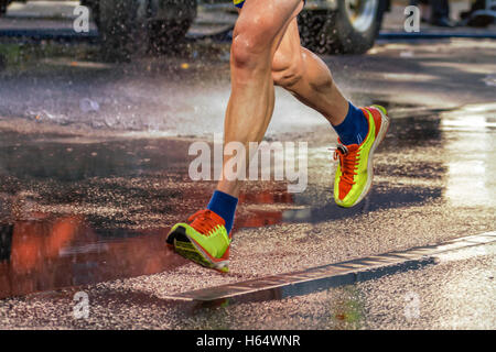 Street runner court le long d'une rue éclairée par des pluies. Banque D'Images