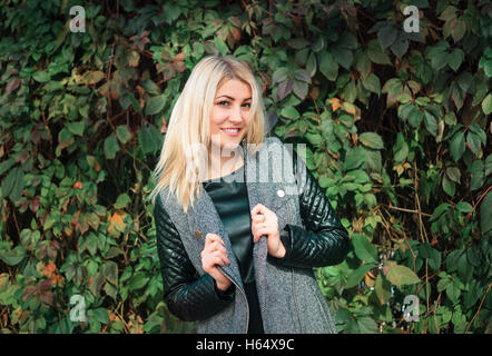 Portrait d'une jolie jeune femme sur un fond de feuilles de lierre vert Banque D'Images