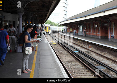 Une femme lisant un journal et d'autres passagers attendent sur la plate-forme dans la gare de Waterloo pour le prochain train. Londres, Angleterre, Grande-Bretagne. Banque D'Images