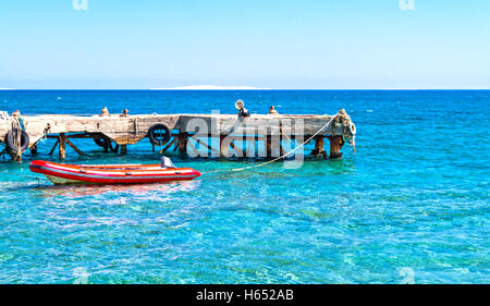 Bateau en caoutchouc près de la jetée dans la mer. Banque D'Images