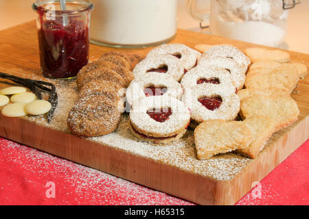 Cookies et biscuits présentés sur une planche en bois avec des ingrédients à côté Banque D'Images