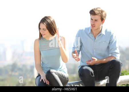 Angry couple arguing dehors, dans un parc avec ville en arrière-plan Banque D'Images