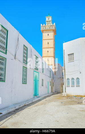 La rue étroite avec les maisons blanches et couvertes de tuiles jaunes minaret, Kairouan, Tunisie. Banque D'Images