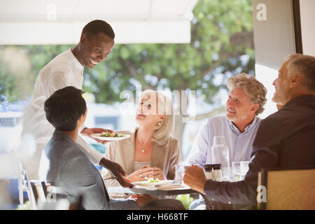 Waiter serving food à des couples au restaurant table Banque D'Images