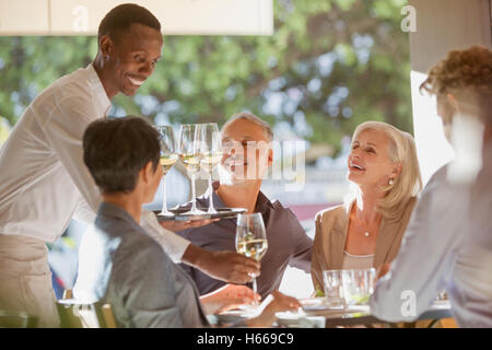 Waiter serving vin blanc à des couples au restaurant table Banque D'Images