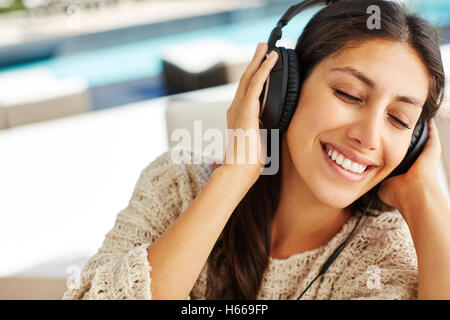 Smiling woman écouter de la musique avec un casque et les yeux fermés Banque D'Images