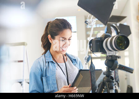 Femme photographe using digital tablet derrière appareil photo en studio Banque D'Images