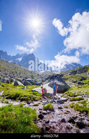 Les randonneurs traversant un ruisseau sur le Grand Balcon Nord, vallée de Chamonix, Alpes, France. Banque D'Images