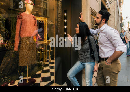 Jeune couple de touristes regardant une fenêtre de mode magasin de Via del Corso, Rome, Latium, Italie Banque D'Images