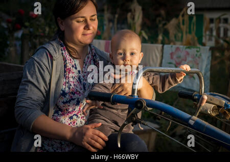 Jeune femme et son fils jouant sur un tracteur dans la campagne. Banque D'Images