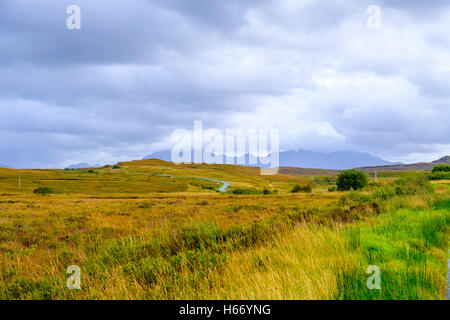 Beau paysage aride de l'île de Skye en Écosse avec petite route sinueuse qui la traverse et les pics des montagnes Cuillin Banque D'Images